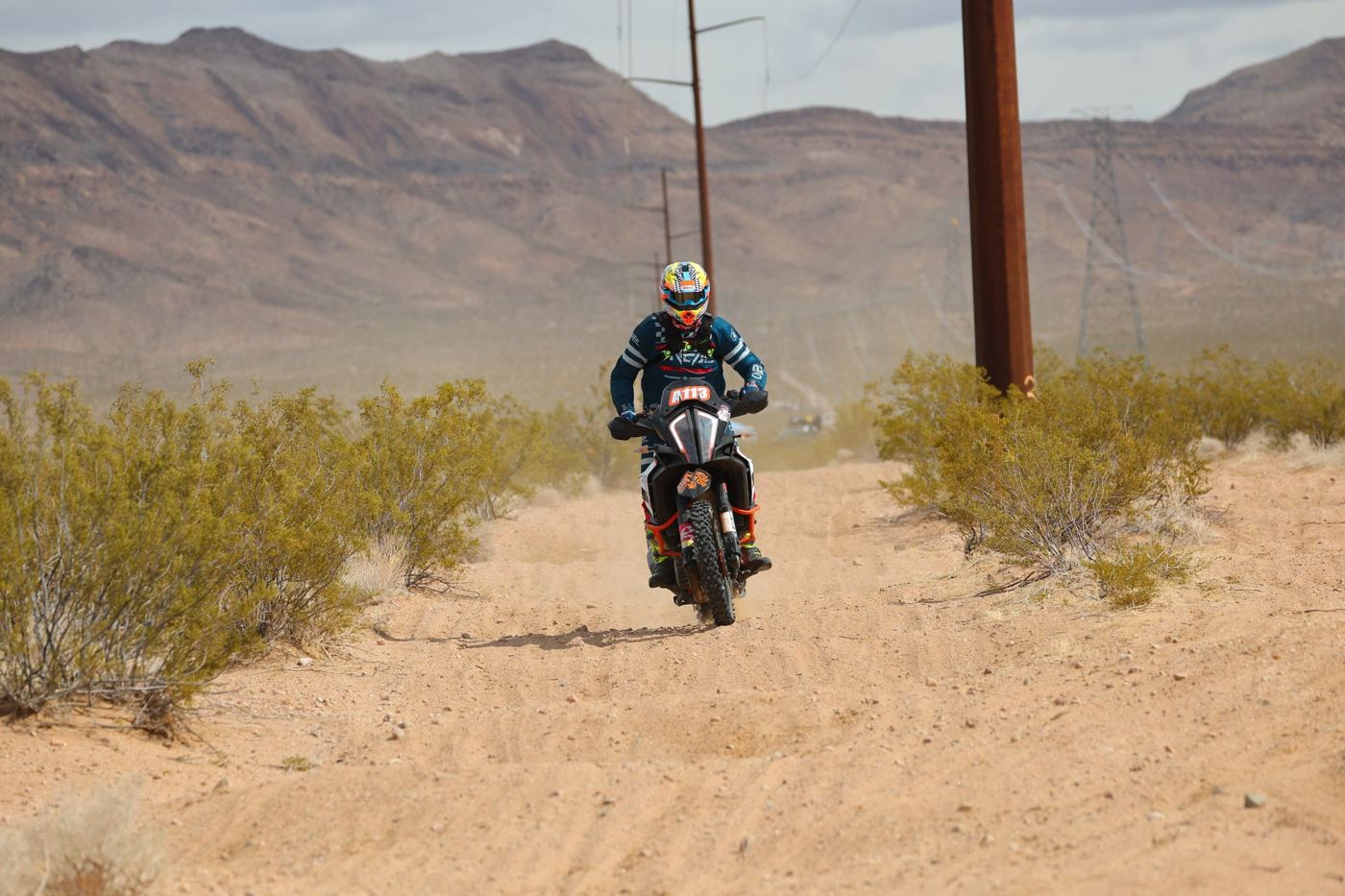The KTM 1290 head-on down a sandy power-line road